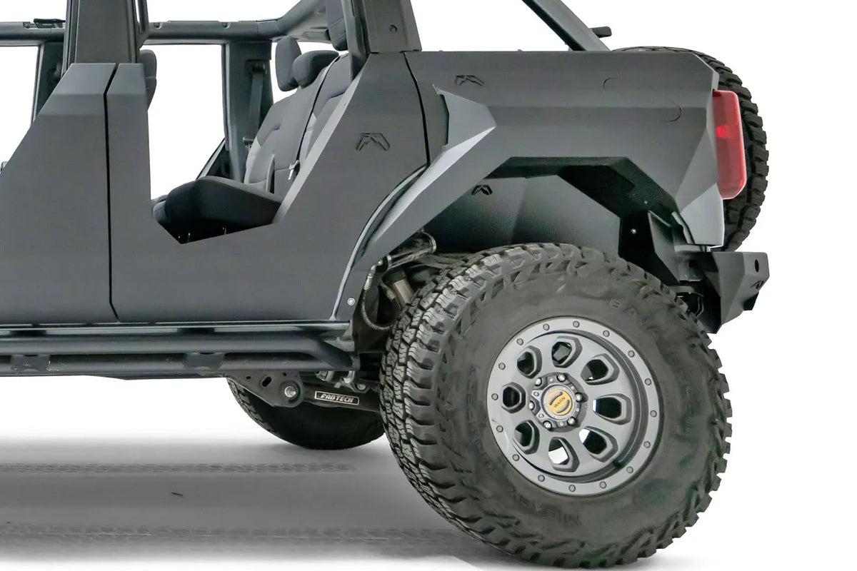 Fab Fours rear inner fender with Fab Fours logo in the driver-side rear wheel well of a lifted gray Ford Bronco with Fab Fours body armor