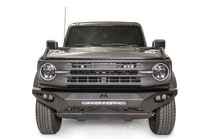 Fab Fours Vengeance front bumper on a black Ford Bronco, straight-on front studio view, showing the sculpted bumper face, center light bar and cube light pods