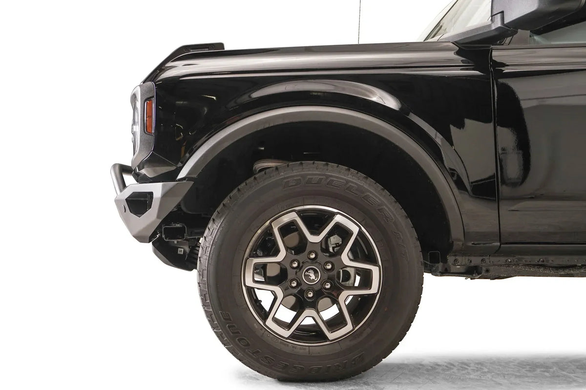 Fab Fours Vengeance front bumper with pre-runner guard on a black Ford Bronco, close-up of the driver-side bumper end, showing the pre-runner tube, end cap and tire clearance