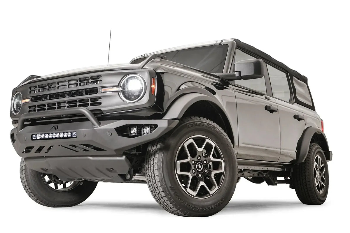 Fab Fours Vengeance front bumper with pre-runner guard on a black Ford Bronco, front driver-side three-quarter studio view, showing the pre-runner hoop, light bar and cube light pods