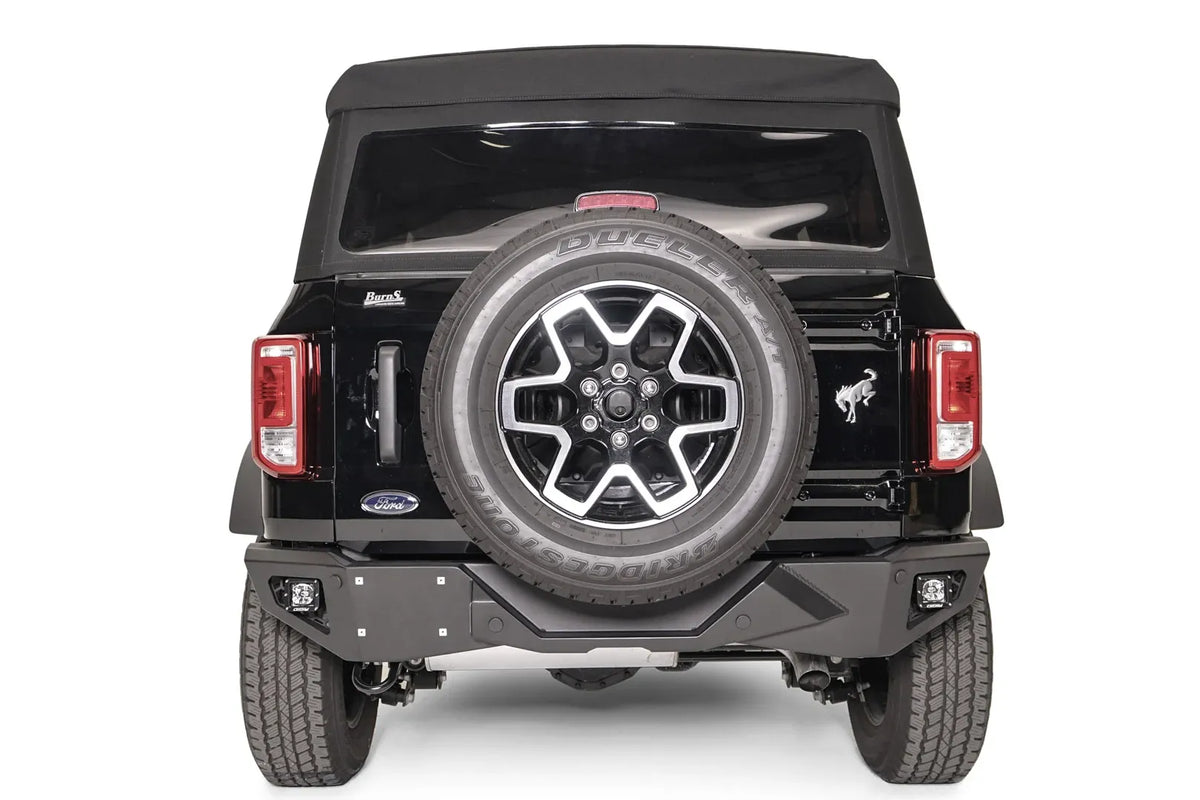 Fab Fours Vengeance rear bumper on a black Ford Bronco, straight rear view, with cube lights in each corner, license plate mount, and tailgate-mounted spare tire