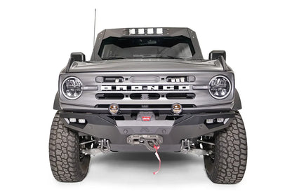 Fab Fours Lifestyle winch front bumper on a lifted gray Ford Bronco, front view, with Warn winch, D-ring shackles, two round pod lights, dual cube lights in each corner, and parking sensors