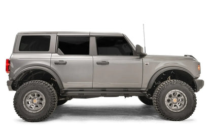 Fab Fours rock slider on a gray four-door Ford Bronco, passenger-side profile, with the low-profile black slider running between the wheels beneath both doors