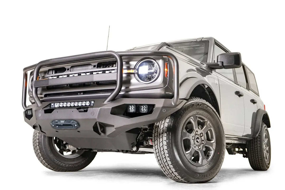 Fab Fours Matrix front bumper with full guard on a gray Ford Bronco, front driver-side three-quarter studio view, showing the full grille guard, light bar and winch fairlead