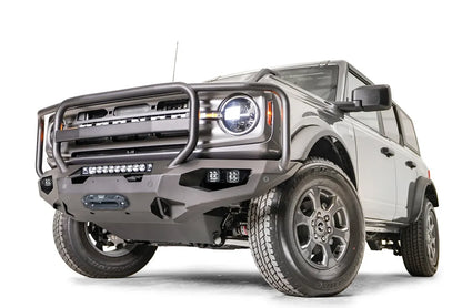 Fab Fours Matrix front bumper with full guard on a gray Ford Bronco, front driver-side three-quarter studio view, showing the full grille guard, light bar and winch fairlead