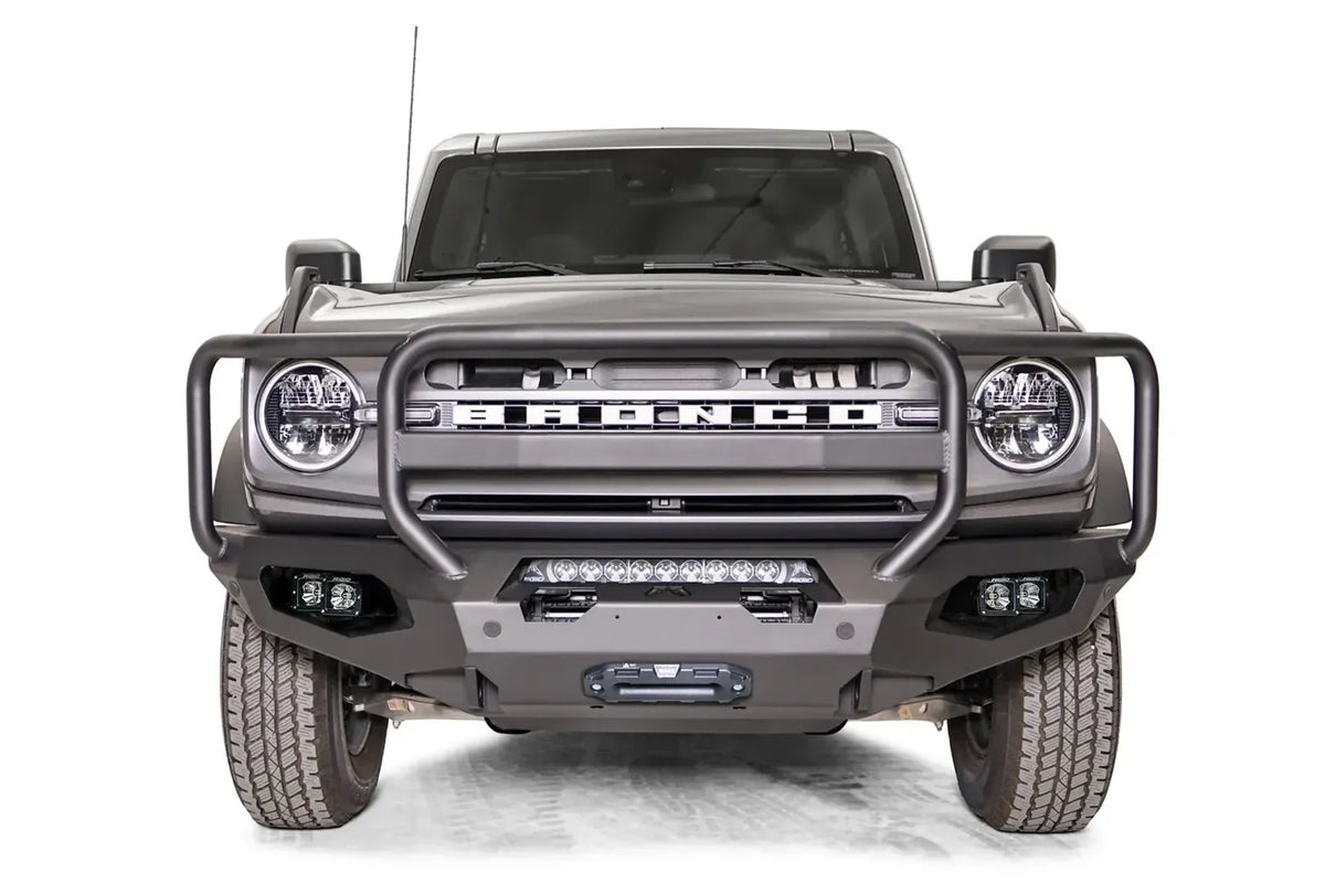 Fab Fours Matrix front bumper with full guard on a gray Ford Bronco, straight-on front studio view, showing the full grille guard, center light bar and winch fairlead