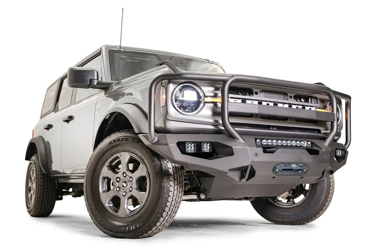 Fab Fours Matrix front bumper with full guard on a gray Ford Bronco, front passenger-side three-quarter studio view, showing the full grille guard, light bar and cube light pods