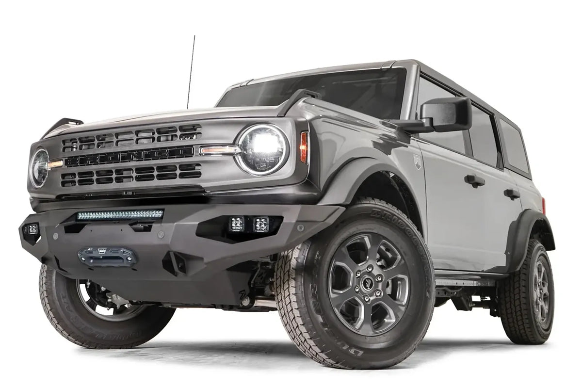 Fab Fours Matrix front bumper on a gray Ford Bronco, front driver-side three-quarter studio view, showing the full-width bumper, light bar and winch fairlead