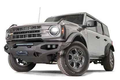 Fab Fours Matrix front bumper on a gray Ford Bronco, front driver-side three-quarter studio view, showing the full-width bumper, light bar and winch fairlead