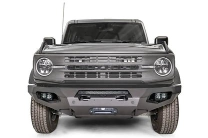 Fab Fours Matrix front bumper on a gray Ford Bronco, straight-on front studio view, showing the full-width bumper, top light bar, winch fairlead and cube light pods