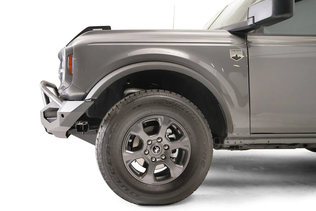 Fab Fours Matrix front bumper with pre-runner guard on a gray Ford Bronco, close-up of the driver-side bumper end, showing the pre-runner tube, end cap and tire clearance