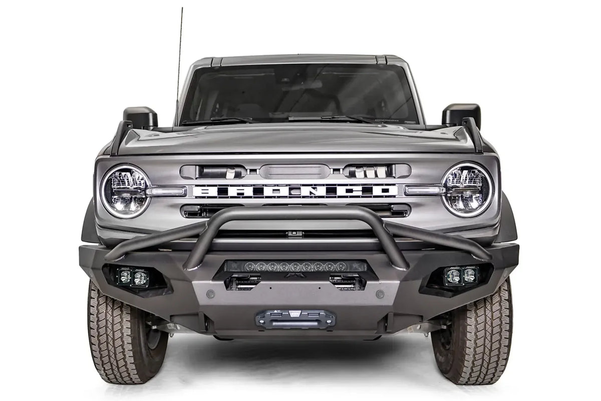 Fab Fours Matrix front bumper with pre-runner guard on a gray Ford Bronco, straight-on front studio view, showing the pre-runner hoop, top light bar and winch fairlead