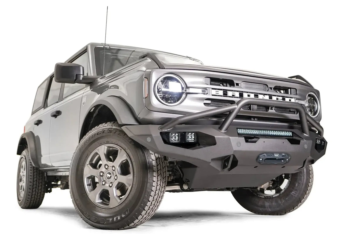 Fab Fours Matrix front bumper with pre-runner guard on a gray Ford Bronco, front passenger-side three-quarter studio view, showing the pre-runner hoop, light bar and cube light pods