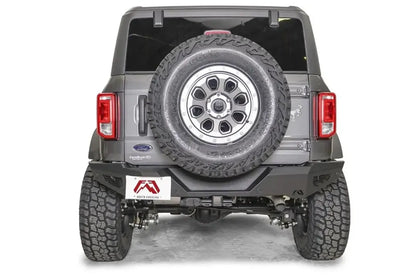 Fab Fours tire carrier relocation bracket on a gray Ford Bronco, rear view, holding the spare tire on the tailgate above a matching Fab Fours rear bumper