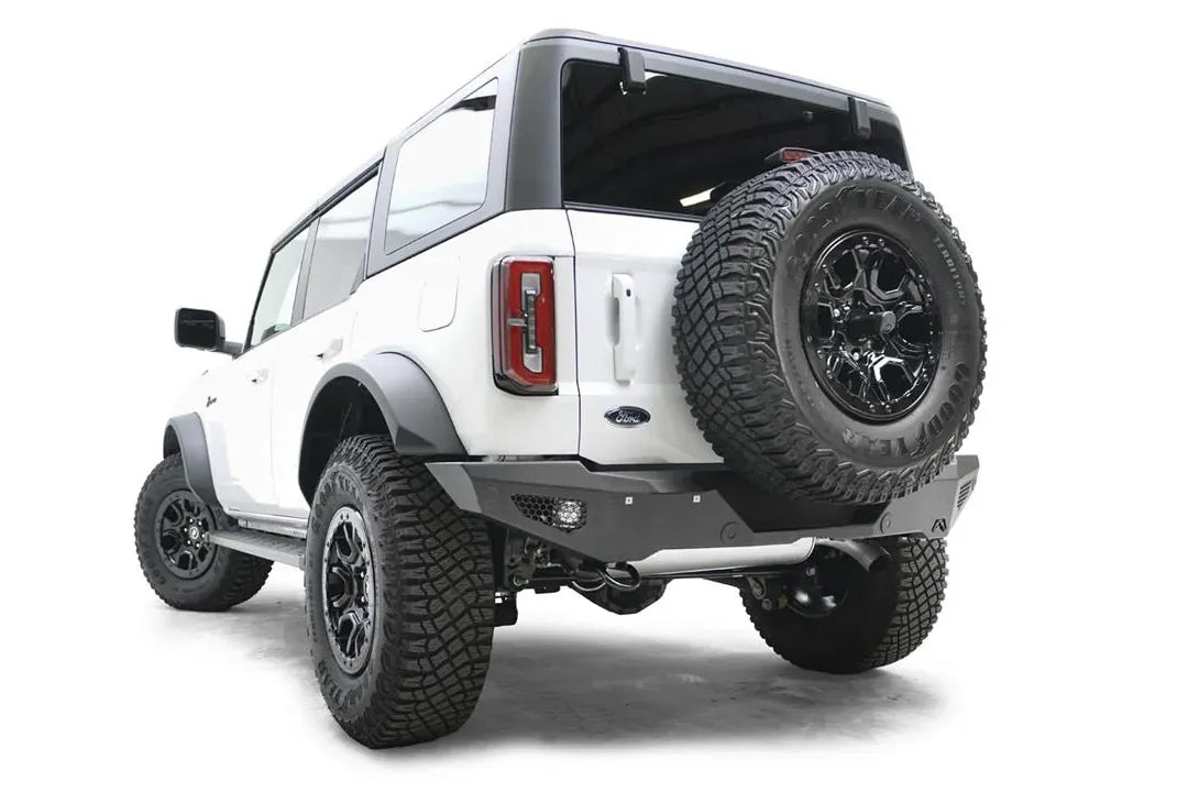 Fab Fours standard rear bumper with honeycomb mesh light openings on a white Ford Bronco with tailgate-mounted spare tire, driver-side rear three-quarter view