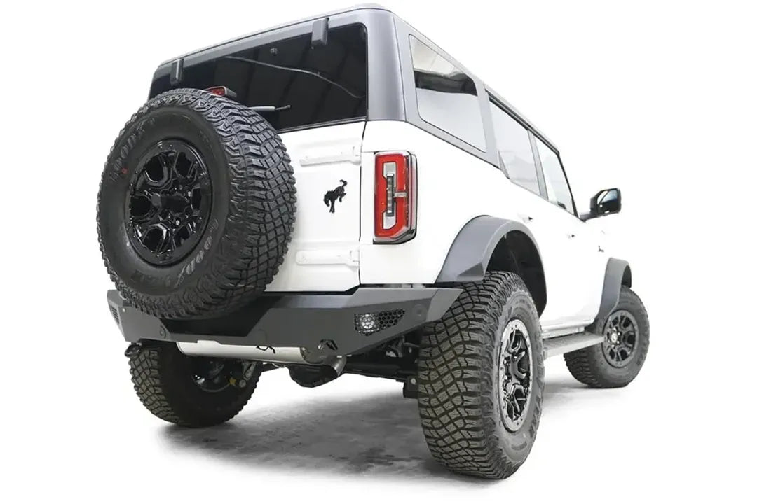 Fab Fours standard rear bumper with honeycomb mesh light openings on a white Ford Bronco with tailgate-mounted spare tire, passenger-side rear three-quarter view