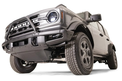 Fab Fours engine skid plate on a gray Ford Bronco fitted with a Fab Fours front bumper with pre-runner hoop, low front driver-side view, showing the skid plate tucked beneath the bumper