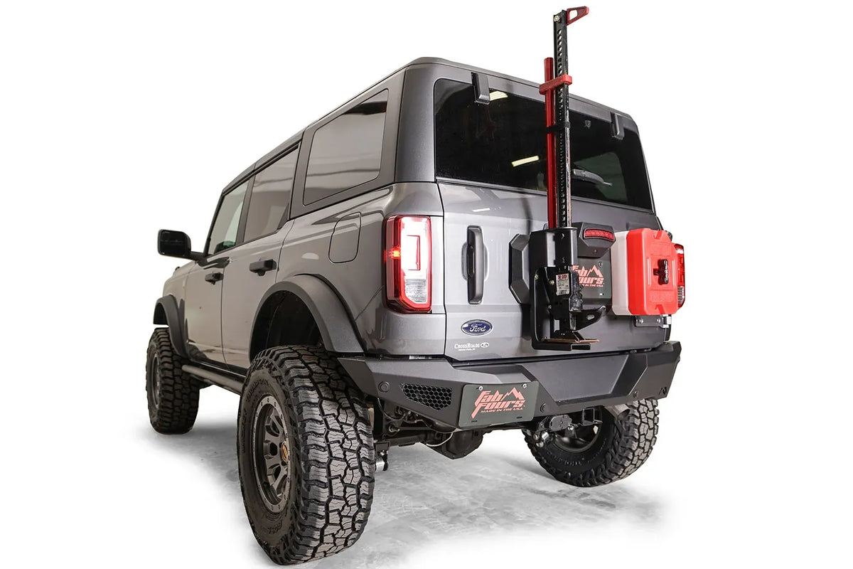 Fab Fours spare tire delete on a gray Ford Bronco, rear driver-side view, carrying a high-lift jack and red fuel can on the tailgate