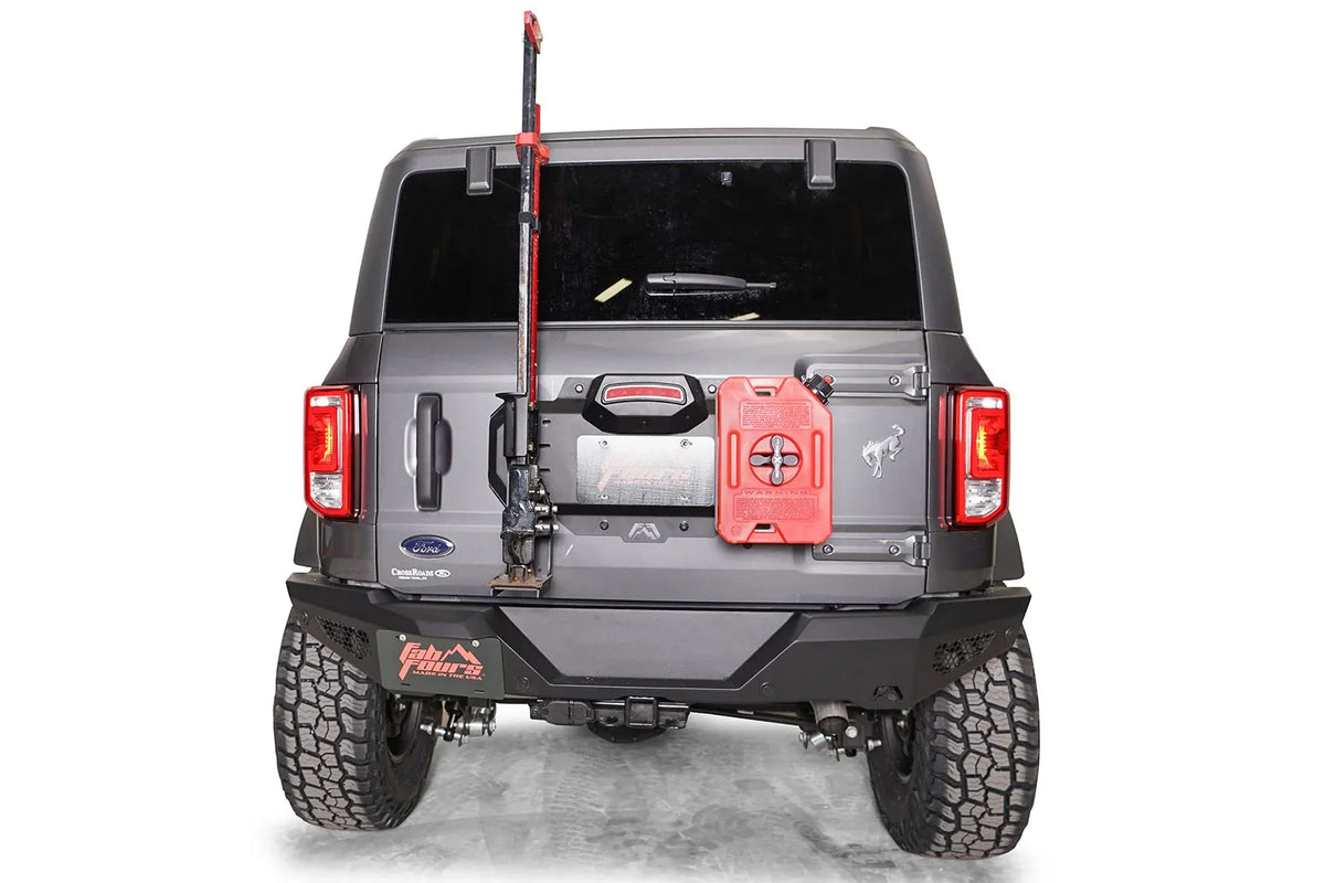 Fab Fours spare tire delete on a gray Ford Bronco, rear view, with a high-lift jack and red fuel can mounted to the tailgate plate above the rear bumper