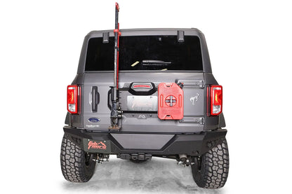 Fab Fours spare tire delete on a gray Ford Bronco, rear view, with a high-lift jack and red fuel can mounted to the tailgate plate above the rear bumper