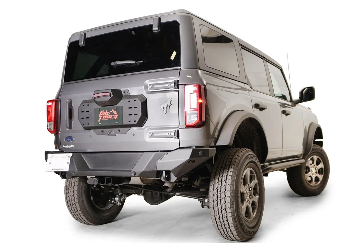 Fab Fours spare tire delete on a gray Ford Bronco, rear passenger-side view, showing the clean tailgate plate with Fab Fours license plate frame and rear bumper