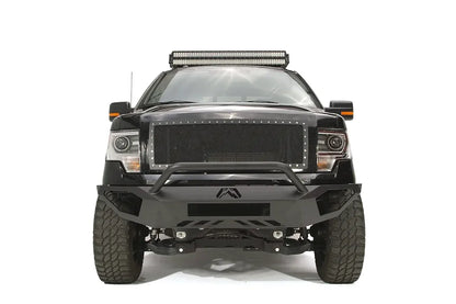 Fab Fours Vengeance front bumper with pre-runner guard on a black Ford F-150, straight-on front studio view, showing the pre-runner hoop, center logo plate and lower skid section