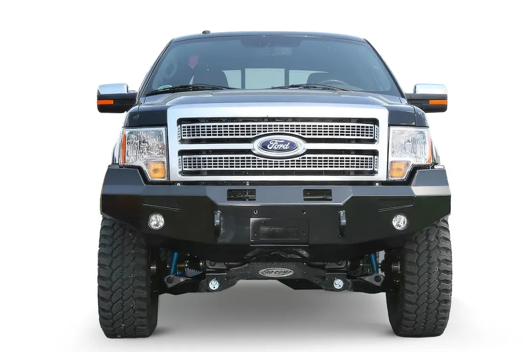 Fab Fours Premium Winch front bumper on a black Ford F-150, straight-on front view on a white background, showing the heavy-duty bumper face, winch opening and fog lights