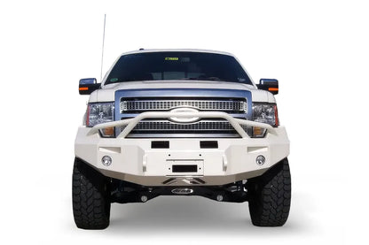 Fab Fours Premium Winch front bumper with pre-runner guard on a white Ford F-150, straight-on front view on a white background, showing the pre-runner hoop, heavy-duty bumper face and fog lights