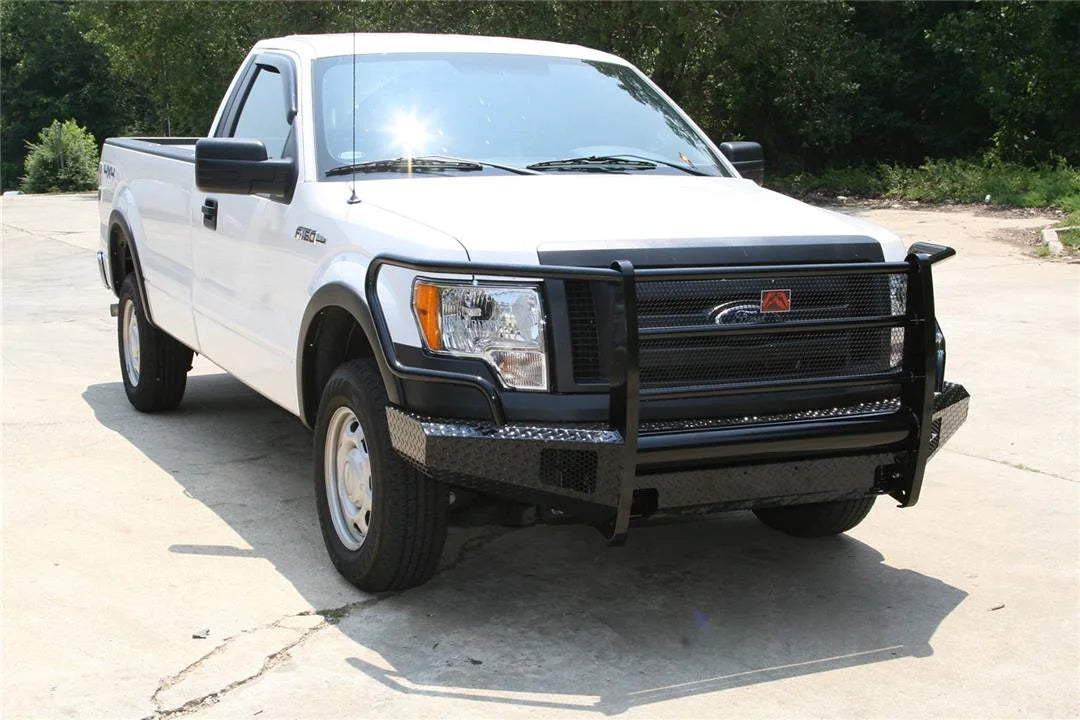 Fab Fours Black Steel front ranch bumper with full guard on a white Ford F-150 regular cab, front passenger-side three-quarter view outdoors, showing the full grille guard, diamond-plate bumper and wraparound wings