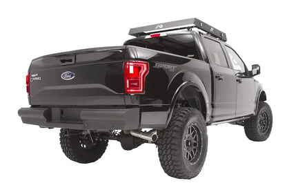 Fab Fours Black Steel Elite rear bumper on a black Ford F-150, rear driver-side three-quarter studio view, showing the smooth rear bumper, center plate pocket and hitch receiver