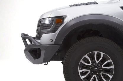 Fab Fours Vengeance front bumper with pre-runner guard on a silver Ford Raptor, close-up of the driver-side bumper end, showing the pre-runner tube, angular end cap and tire clearance