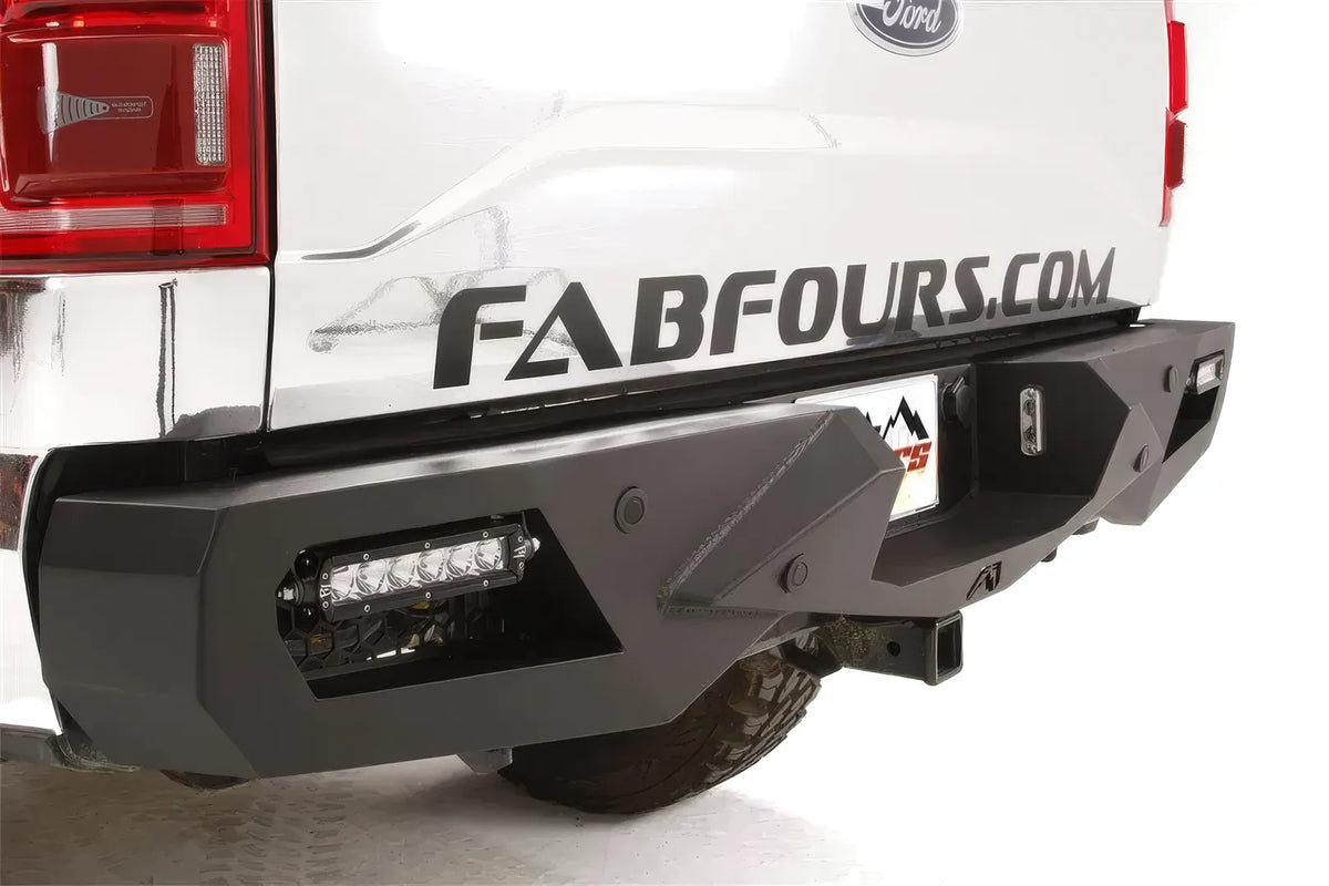Fab Fours Vengeance rear bumper on a white Ford F-150, close-up of the rear bumper on a white background, showing the angular corner, integrated light bar and hitch receiver
