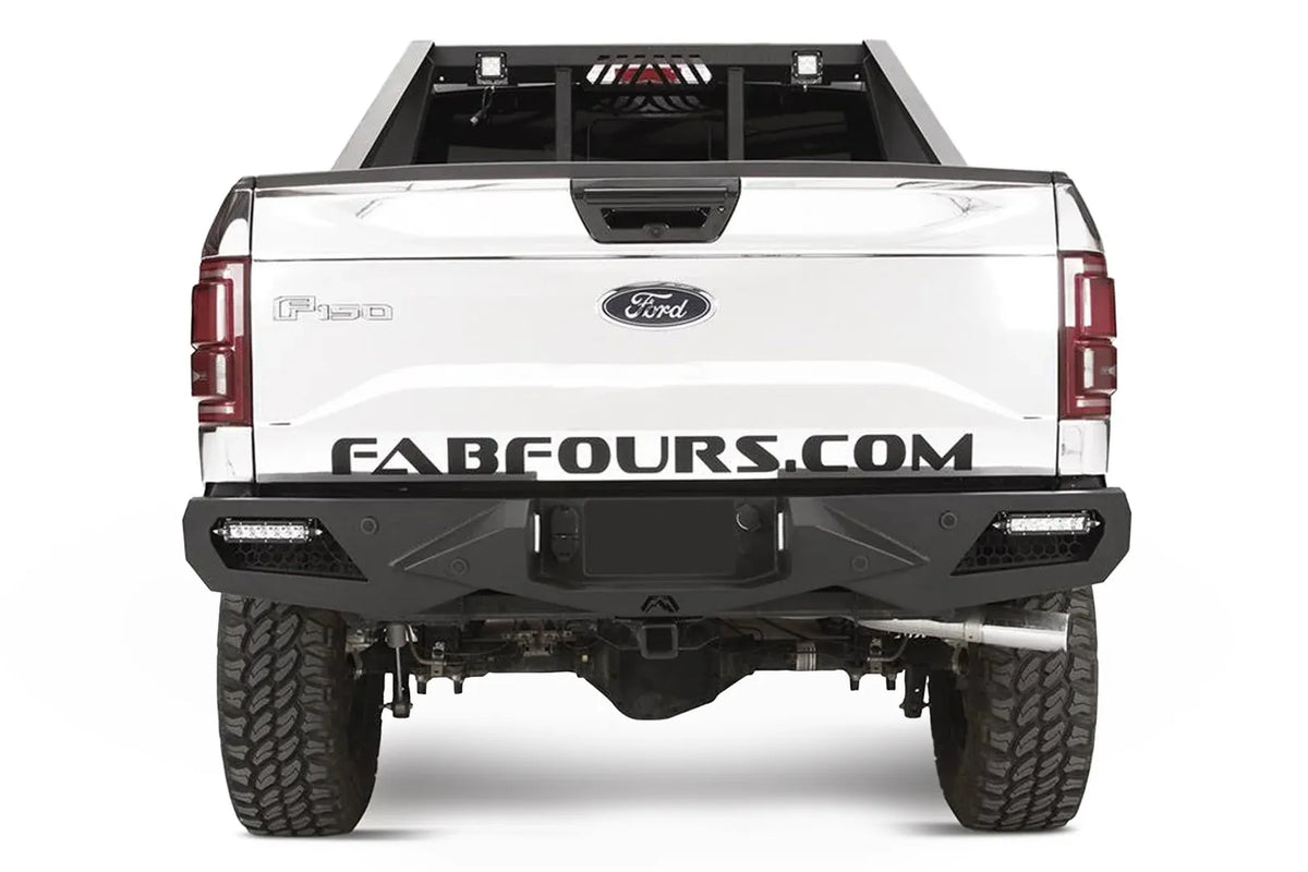 Fab Fours Vengeance rear bumper on a white Ford F-150, straight-on rear studio view, showing the sculpted rear bumper, corner light bars and center hitch opening