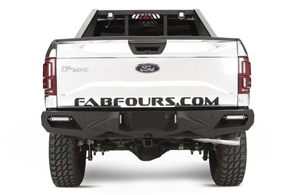 Fab Fours Vengeance rear bumper on a white Ford F-150, straight-on rear studio view, showing the sculpted rear bumper, corner light bars and center hitch opening