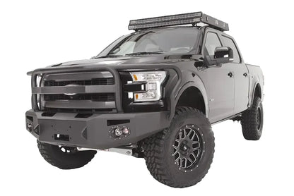 Fab Fours Premium Winch front bumper with full guard on a black Ford F-150, front driver-side three-quarter studio view, showing the full grille guard, heavy-duty bumper and round fog lights