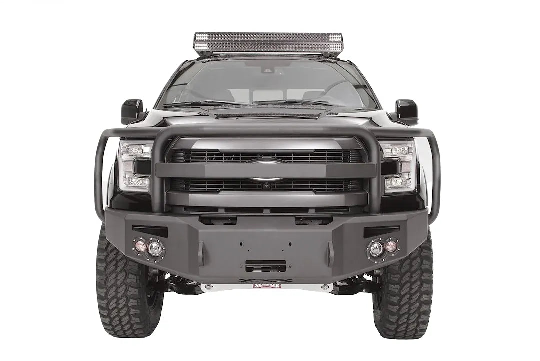 Fab Fours Premium Winch front bumper with full guard on a black Ford F-150, straight-on front studio view, showing the full grille guard, winch-ready center section and round fog lights
