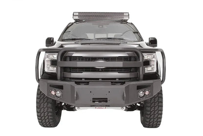 Fab Fours Premium Winch front bumper with full guard on a black Ford F-150, straight-on front studio view, showing the full grille guard, winch-ready center section and round fog lights