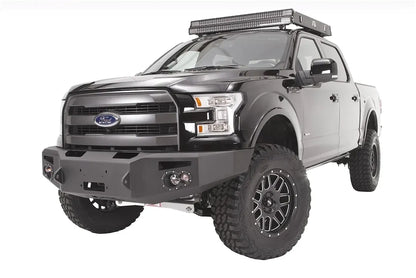Fab Fours Premium Winch front bumper on a black Ford F-150, front driver-side three-quarter studio view, showing the heavy-duty bumper, winch-ready center section and round fog lights