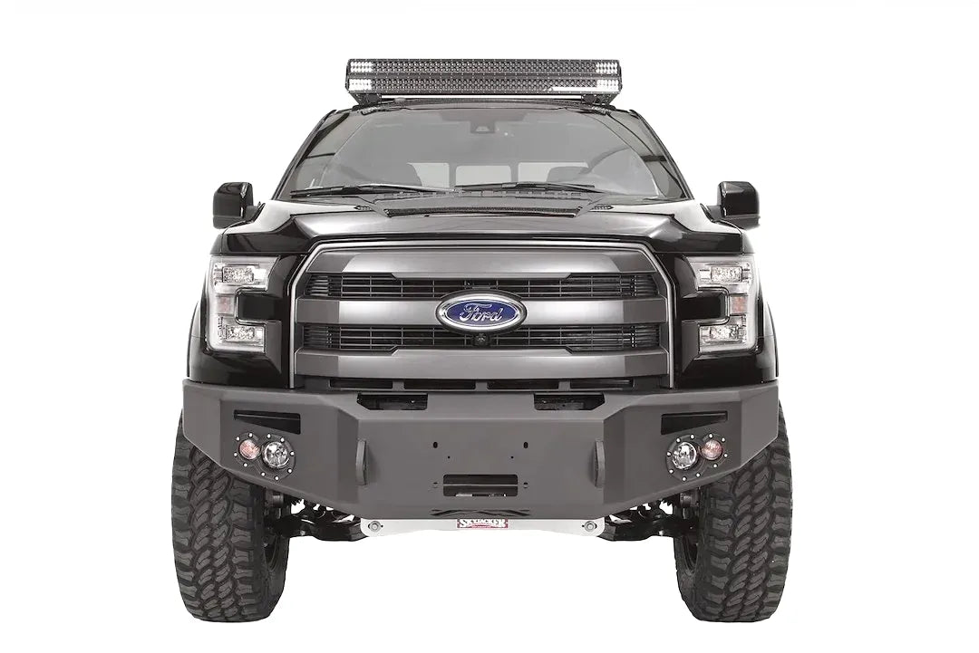 Fab Fours Premium Winch front bumper on a black Ford F-150, straight-on front studio view, showing the heavy-duty bumper face, winch opening and round fog lights