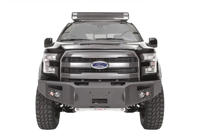 Fab Fours Premium Winch front bumper on a black Ford F-150, straight-on front studio view, showing the heavy-duty bumper face, winch opening and round fog lights