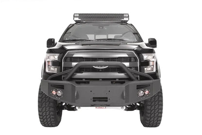 Fab Fours Premium Winch front bumper with pre-runner guard on a black Ford F-150, straight-on front studio view, showing the pre-runner hoop, winch-ready center section and round fog lights