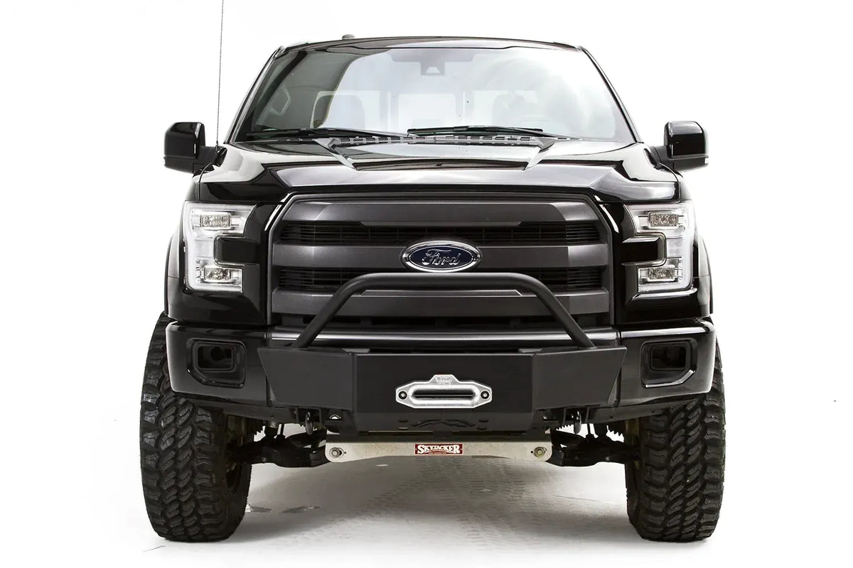 Fab Fours winch mount on a black Ford F-150, straight-on front studio view, showing the pre-runner hoop, winch fairlead and low-profile front plate