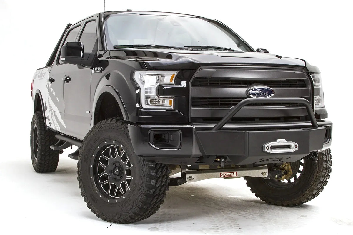 Fab Fours winch mount on a black Ford F-150, front passenger-side three-quarter studio view, showing the pre-runner hoop, winch fairlead and low-profile front plate