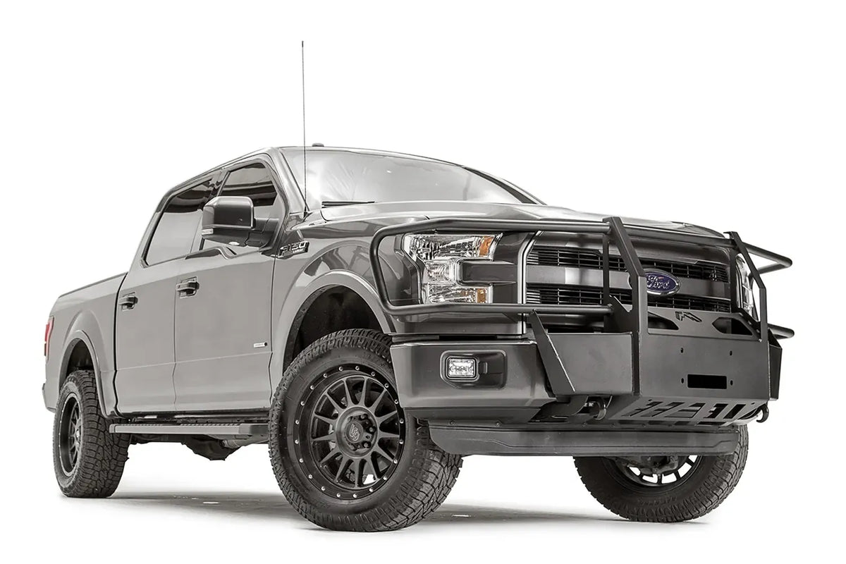 Fab Fours winch mount with full guard on a gray Ford F-150, front passenger-side three-quarter studio view, showing the full grille guard, winch mount plate and skid section