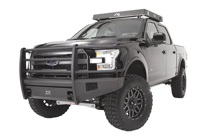 Fab Fours Black Steel Elite front bumper with full guard on a black Ford F-150, front driver-side three-quarter studio view, showing the full grille guard, smooth bumper face and side mesh vents
