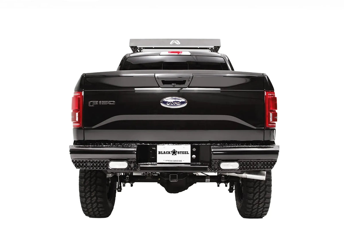 Fab Fours Black Steel rear bumper on a black Ford F-150, straight-on rear view, showing the diamond-plate face, rectangular lights and license plate mount