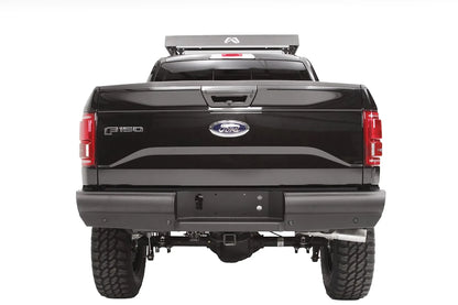Fab Fours Black Steel Elite rear bumper on a black Ford F-150, straight-on rear view, showing the smooth full-width bumper, license plate recess and receiver hitch
