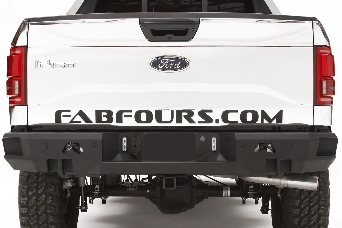 Fab Fours Premium rear bumper on a white wrapped Ford F-150, straight-on rear view, showing the logo cutouts, shackle mounts and center plate recess