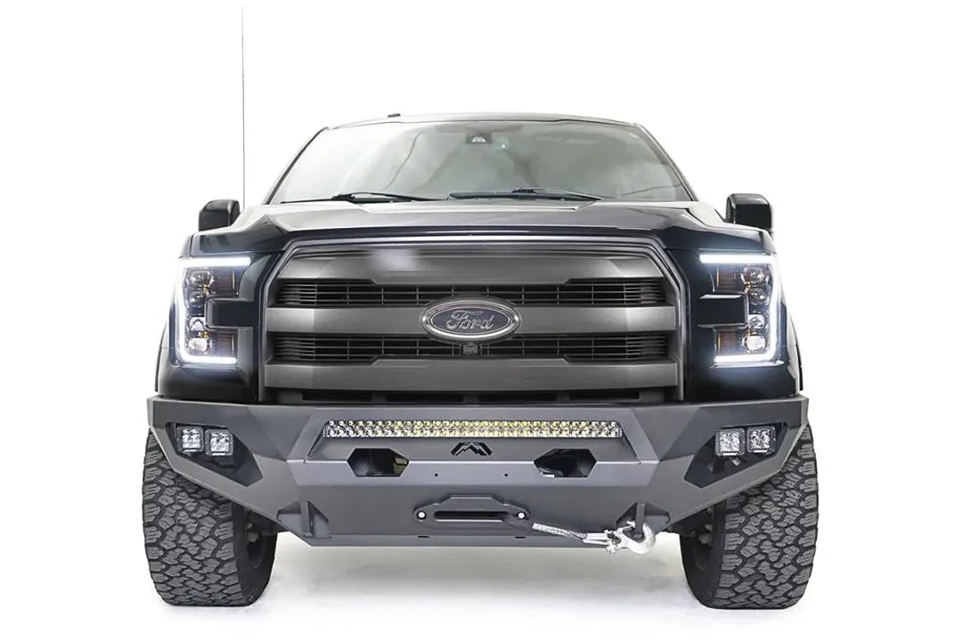 Fab Fours Matrix front bumper on a black Ford F-150, straight-on front view, showing the center light bar, winch fairlead and cube light pods