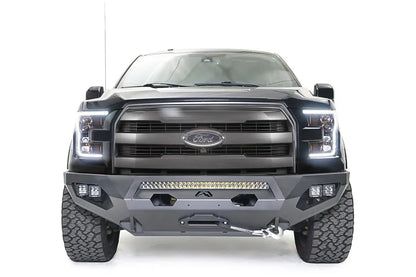 Fab Fours Matrix front bumper on a black Ford F-150, straight-on front view, showing the center light bar, winch fairlead and cube light pods